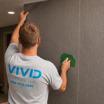 Man installing textured wallpaper with a smoothing tool.