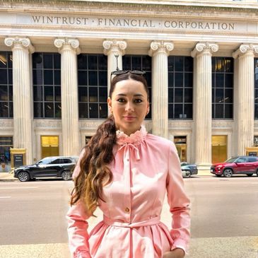 Woman in a pink dress standing in front of a financial corporation building.