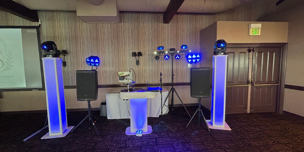 DJ setup with blue lights and speakers in a room.
