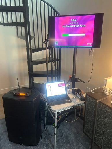 Karaoke setup with screen, microphones, and speaker.