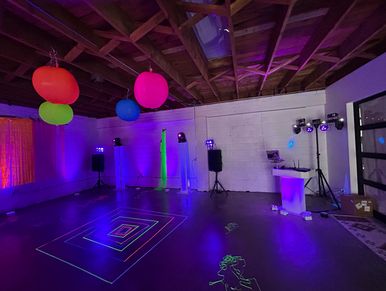 Colorful party room with neon lights and balloons.