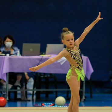 Young gymnast performing a routine in a competition setting.
