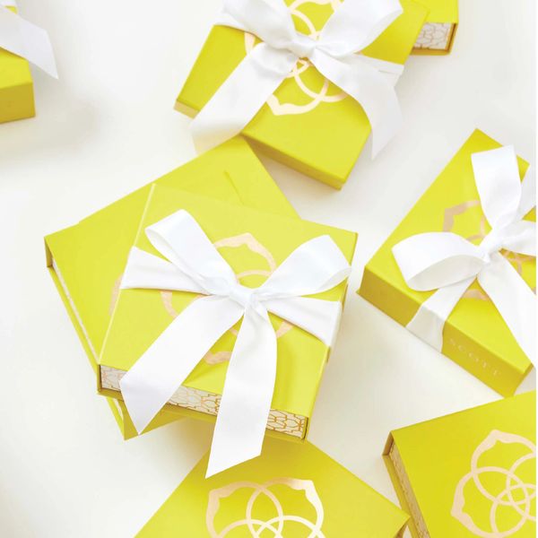Elegant yellow gift boxes adorned with white ribbons, arranged neatly.