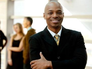 Confident man in a suit smiling with crossed arms.