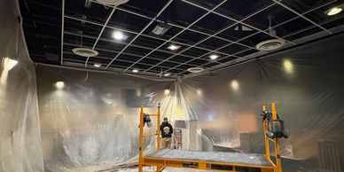 A person working inside a room covered with protective plastic sheeting.