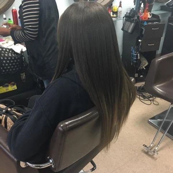 Person with long, straight hair sitting in a salon chair.