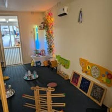 A cozy sensory playroom with interactive toys and soft lighting.