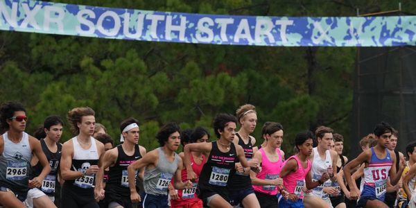 Runners start a cross country race under a banner that says NXR South Start.