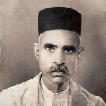 Black-and-white portrait of a serious man wearing a traditional hat.
