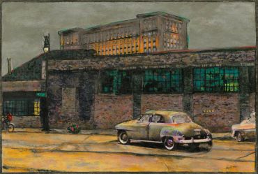 Vintage cars parked near an old brick building with a large illuminated structure in the background.