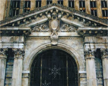 Ancient stone building entrance with columns and decorative carvings.