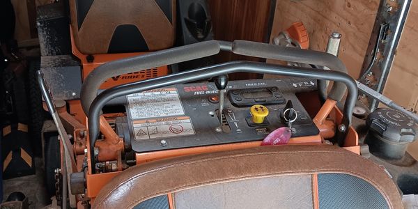 SCAG riding lawn mower parked in a wooden shed.