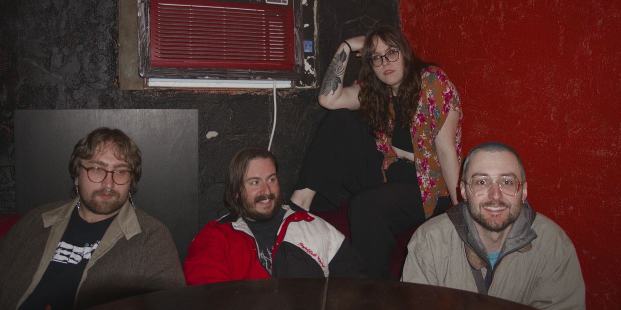 Four friends sitting in a cozy room with dark and red walls.
