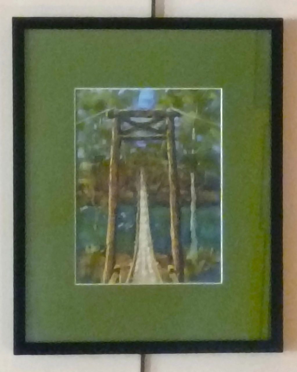 Framed photo of a suspension bridge in a forested area.