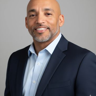 Confident man in a suit smiling warmly at the camera.