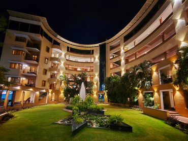 Curved hotel building illuminated at night with a garden courtyard.
