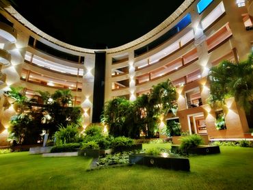 Modern residential building with illuminated courtyard garden at night.