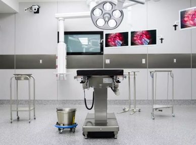 Modern operating room with surgical table and monitors.