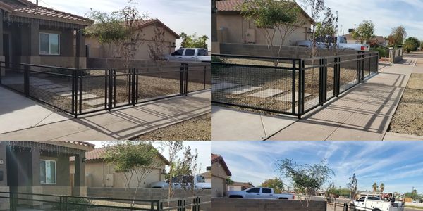 A black metal fence surrounding a small front yard in a suburban neighborhood.