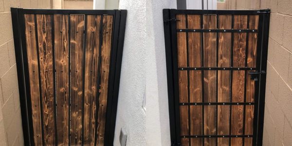 Wooden gate with black metal frame in a narrow passage.