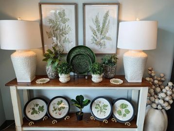 Elegant botanical-themed decor with lamps and green accents on a wooden shelf.