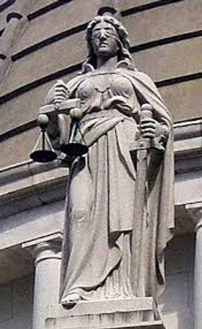 Stone statue of Lady Justice holding scales and a sword.