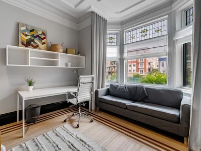 Bureau minimaliste avec canapé gris près d'une baie vitrée.