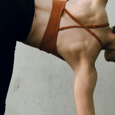 Close-up of a person in workout attire stretching against a wall.