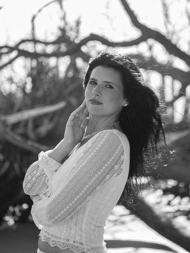 Black and white portrait of a woman with flowing hair in a natural setting.