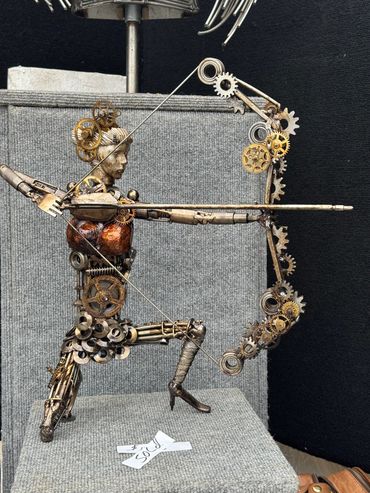 Metal sculpture of an archer made from gears and mechanical parts.