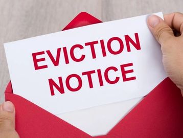 Hands holding an eviction notice coming out of a red envelope.