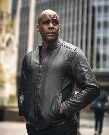 Man in black leather jacket standing outdoors.