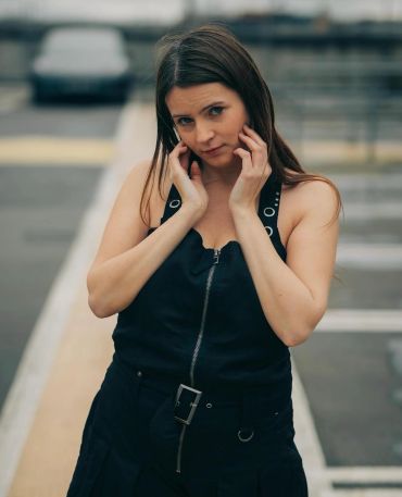 Woman posing outdoors in a black outfit.