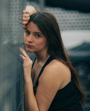 Thoughtful woman leaning on a fence.