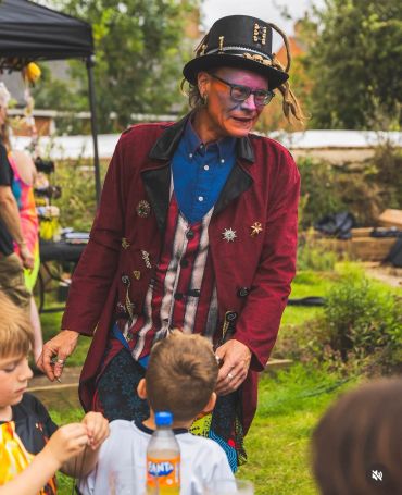 Man in colorful costume entertaining children outdoors.