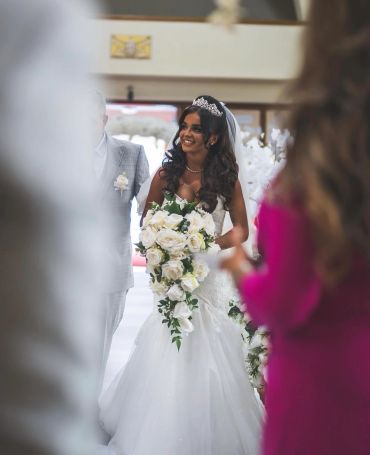 Bride in white wedding dress holding a cascading bouquet.