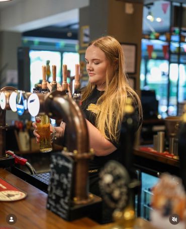 Bartender pouring a draft beer in a pub.