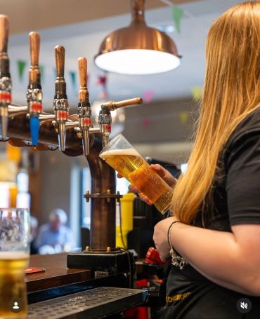 Bartender pouring beer from tap into a glass.