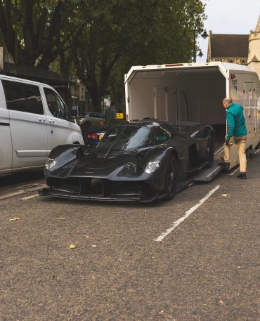 A sleek black sports car being loaded into a white trailer.