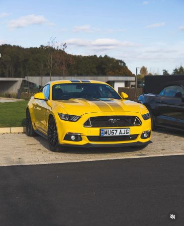 Bright yellow Ford Mustang parked in a driveway.