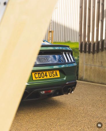 Rear view of a green Ford Mustang Mach 1 with a UK license plate.