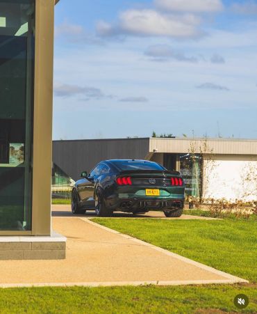 Black sports car parked near modern buildings.