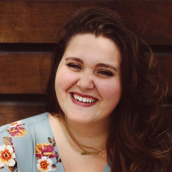 Smiling woman with wavy hair in a floral dress against a wooden background.Sterling Tax Service tax preparation tax solutions bookkeeping