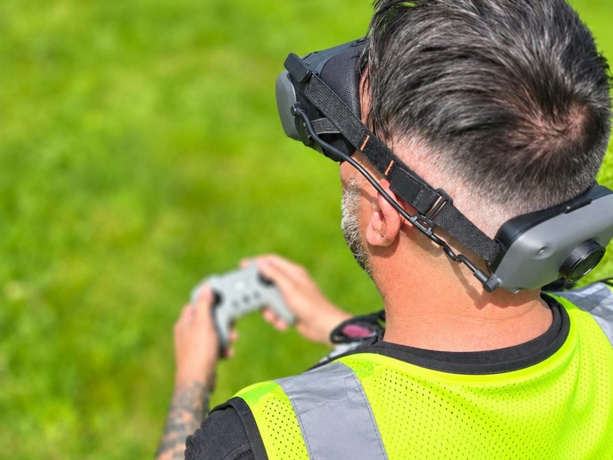 Man wearing VR headset with controller on green field.
