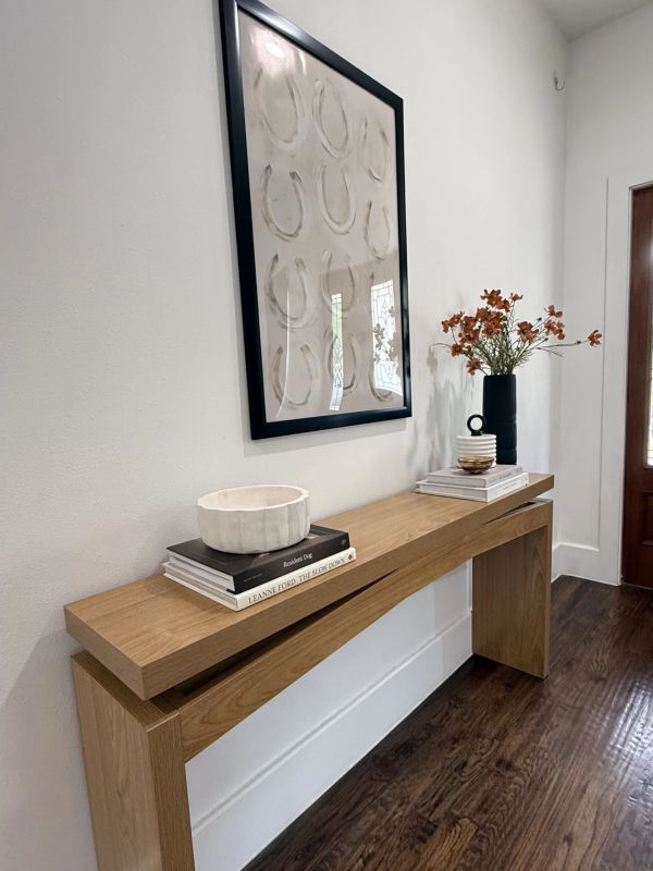 Minimalist entryway with wooden console, abstract wall art, and decor.