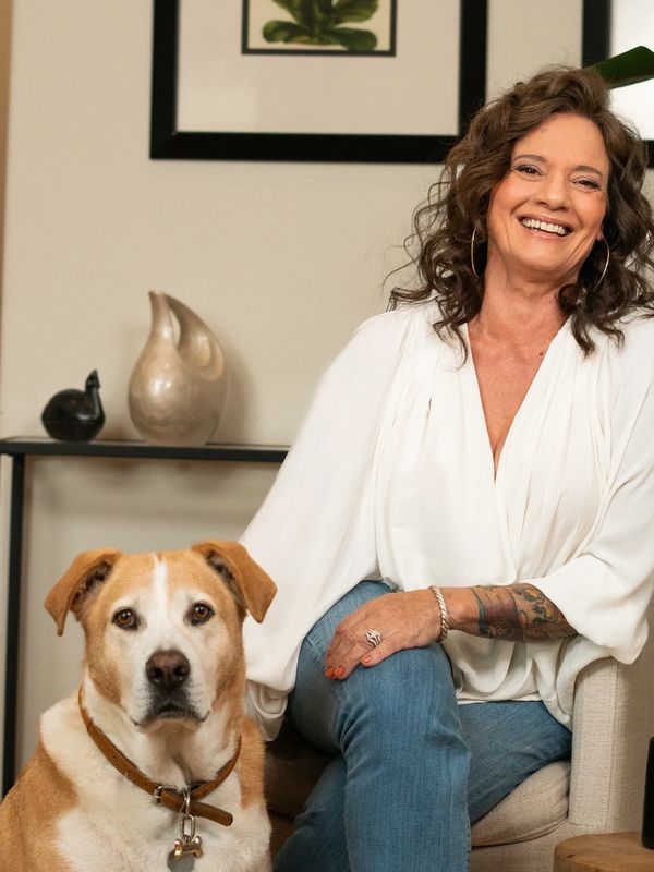 Smiling woman in white blouse sitting with her dog.