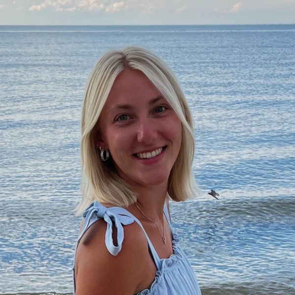 Smiling woman in a blue dress by the sea.