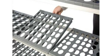 Person holding a perforated metal panel with circular holes.