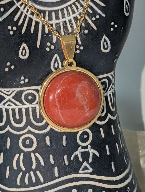 Gold necklace with a round red stone pendant.