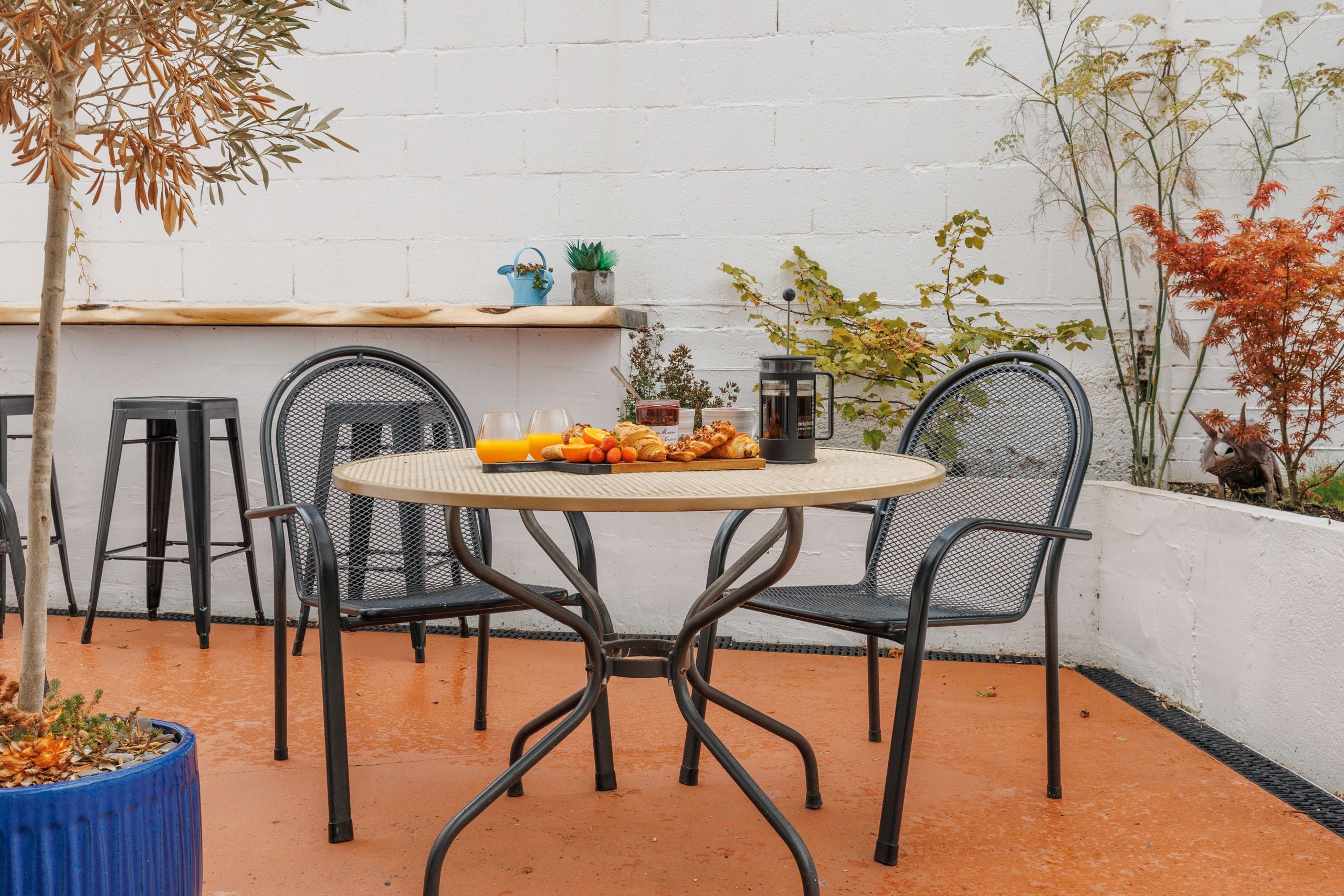 Outdoor patio with metal chairs and a table set with croissants and orange juice.